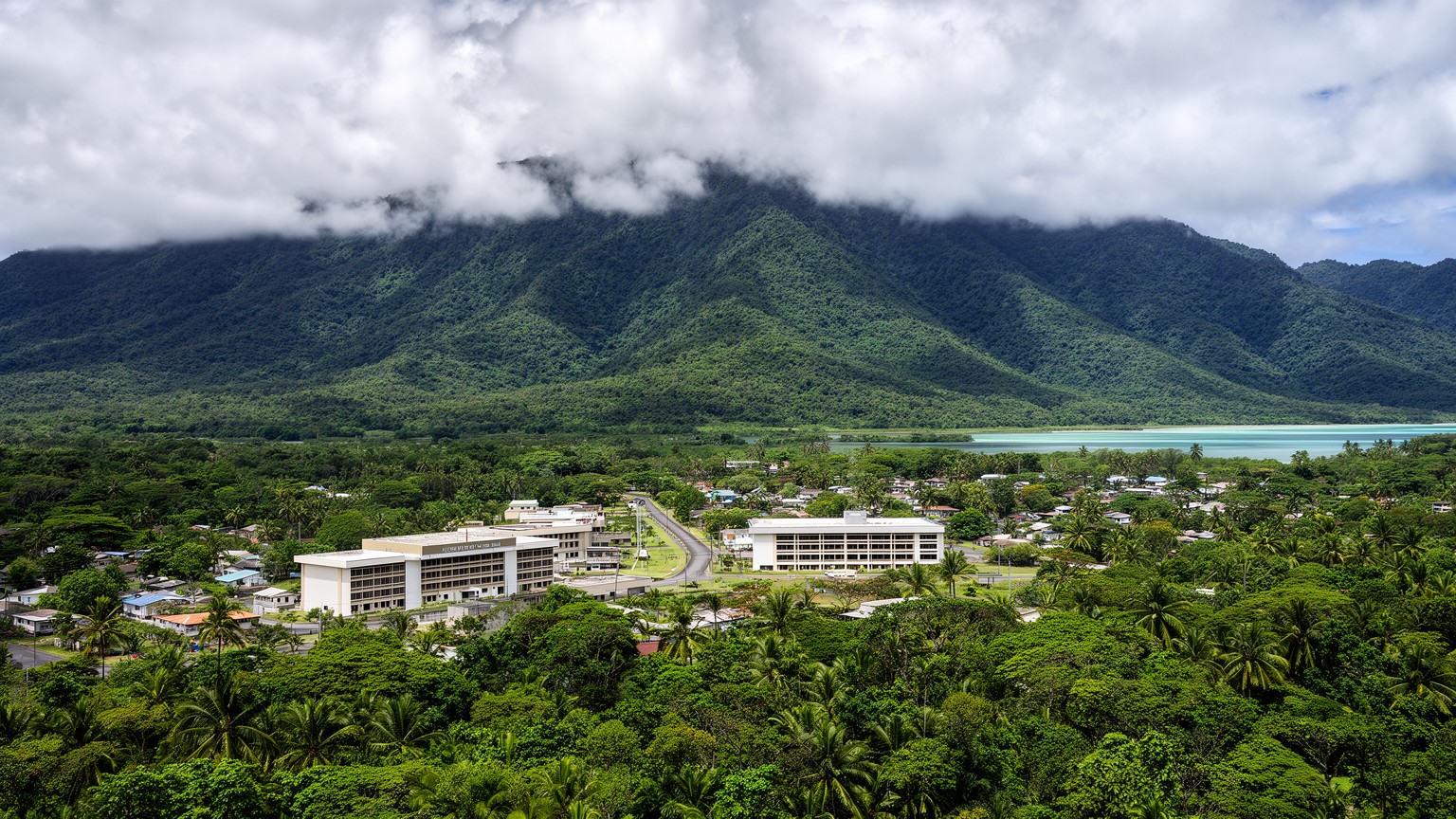 ポンペイ島の雨林、山並み、連邦政府庁舎、礁湖が重なるパリキールの都市景観
